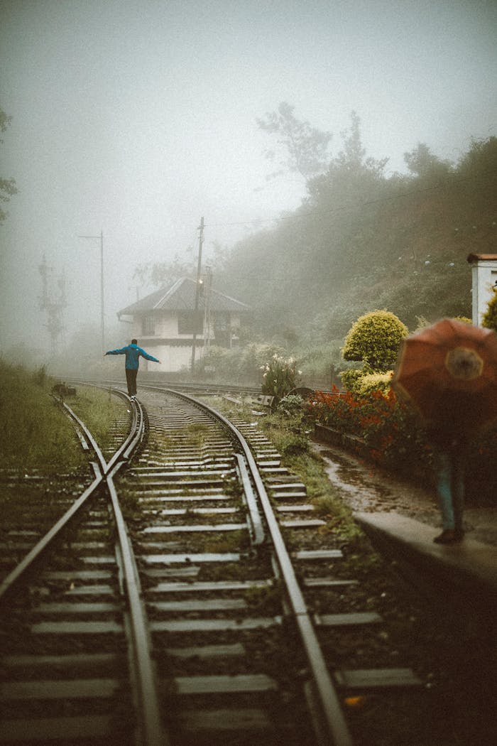 A person walking along foggy train tracks in scenic Sri Lanka, embodying a sense of adventure.