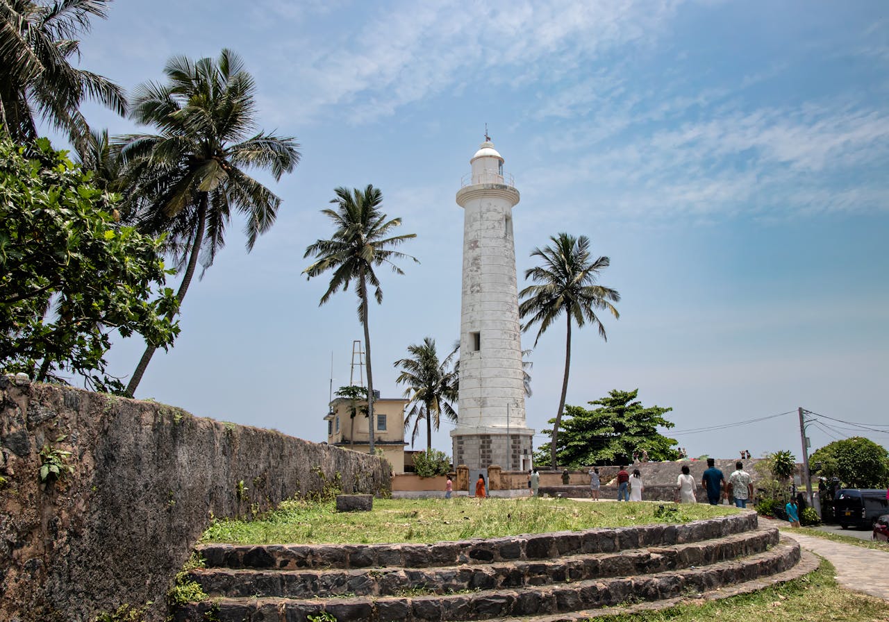 A picturesque view of Galle Lighthouse surrounded by palm trees in Sri Lanka's Galle Fort.